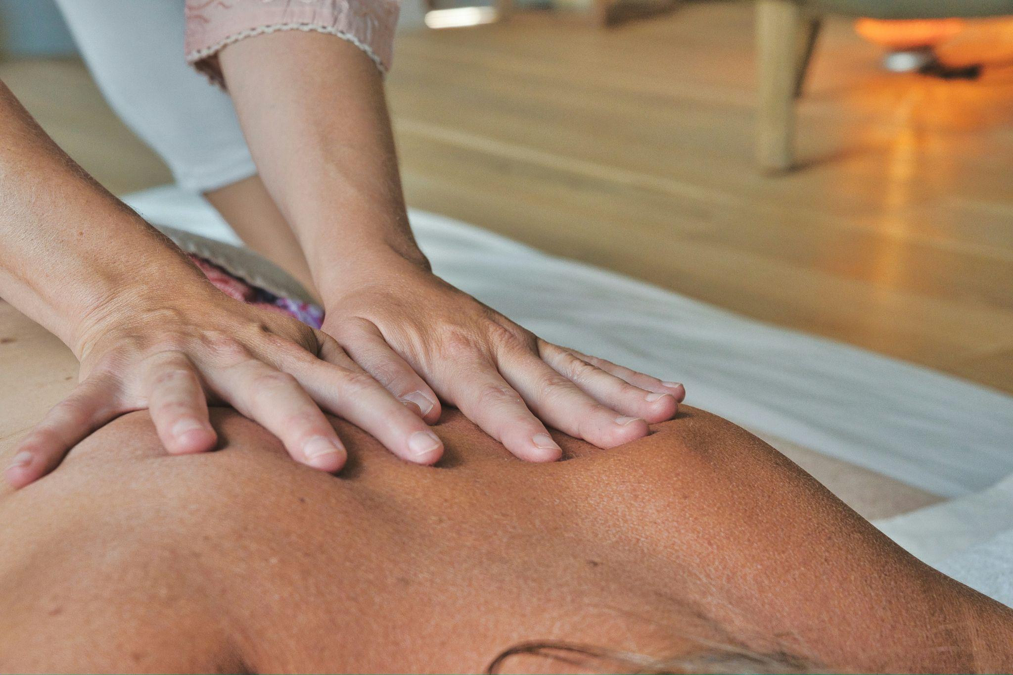A massage therapist applies pressure to a client’s back during an in-home massage in Clovis session.