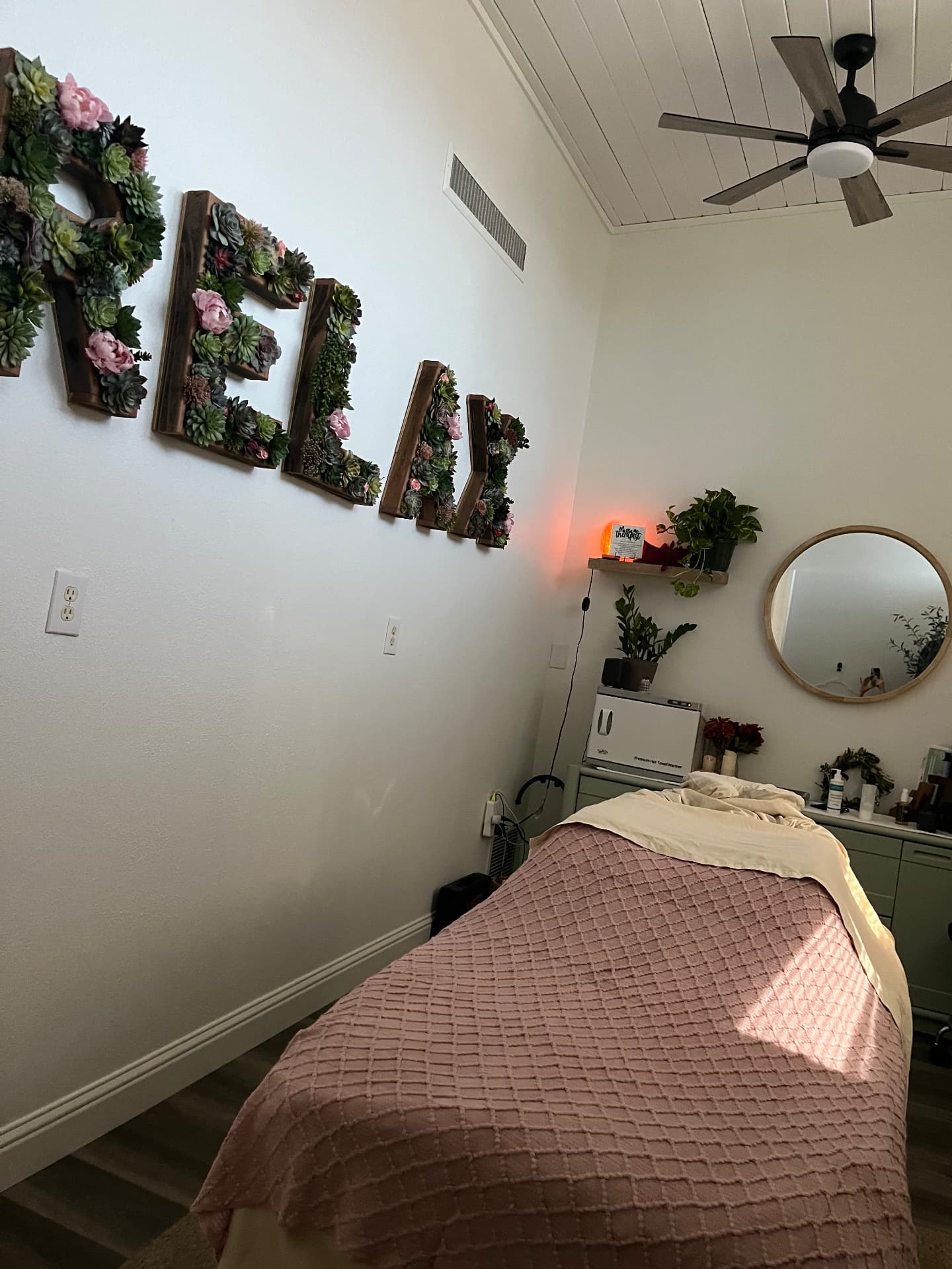 Serenity Garden treatment room with a succulent RELAX wall sign and a massage table
