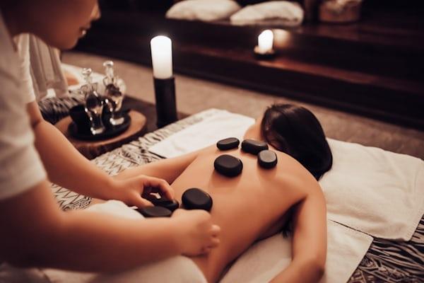 Therapist performing hot stone therapy in California with heated basalt stones.